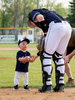 (photo by Bruce Brierley)
Senior High junior John Anderson (13) hands the ball and gets a fist pump from Dave Aker’s grandson Emmett who threw out the ceremonial first pitches.